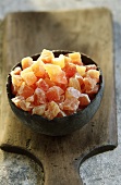 Terracotta bowl of candied papaya on a wooden board