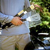 Man holding various barbecue tools