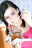 Young woman holding honey jar with honey spoon