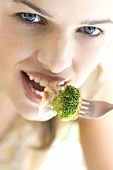 Young woman eating broccoli with fish