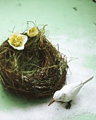 Grass bird's nest with white wooden bird