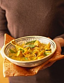 Woman holding plate of chicken and pumpkin curry