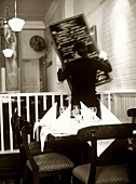 Kellner in einem Restaurant hängt Menütafel auf