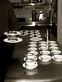 Coffee cups and plates of biscuits in restaurant kitchen