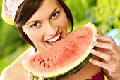 Woman biting into a piece of melon