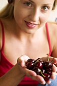 Young woman holding cherries in her hands