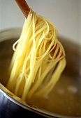 Gekochte Spaghetti mit Holzlöffel aus dem Kochwasser heben