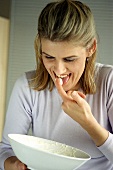 Woman taking nibbles out of bowl with her fingers