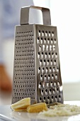Four-sided grater; pieces of Parmesan; grated Parmesan