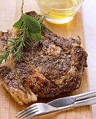 Peppered steak on a wooden board, cutlery beside it