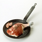 Raw duck leg in a cast-iron frying pan