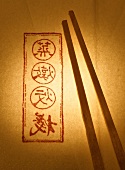 Hölzerne Essstäbchen auf Papier mit asiatischen Schriftzeichen
