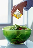 Drizzling green salad with olive oil