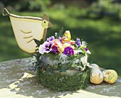 Easter nest with spring flowers, ivy, grass, chocolate bunny