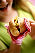 Woman holding hot dog in a napkin