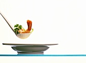 Shrimp tail and parsley on soup ladle over plate