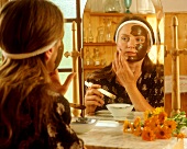 Woman applying healing earth and marigold face mask
