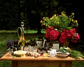 Naturkosmetik, Heilpflanzen und Blumen auf Tisch im Freien