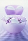 Two purple bowls with white eggs and lilac