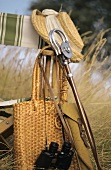 Chair with bag, binoculars, fishing rod and hat in open air