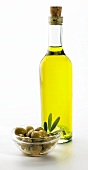 A bowl of green olives and bottle of olive oil