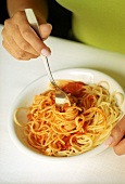 Twisting spaghetti with tomato sauce around fork