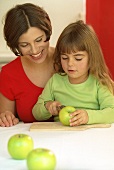 Mutter und Tochter schneiden einen Apfel