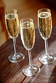 Three champagne glasses on wooden table (grainy effect)