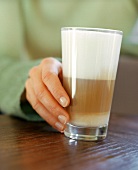 Hand holding a glass of latte macchiato (grainy effect)