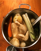 Boiling fowl with vegetables in pan