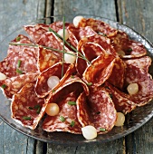 Sliced salami served with pearl onions