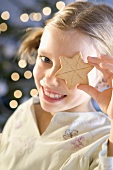 Smiling girl holding star biscuit in front of her eye