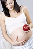 Pregnant woman looking happy with apple in her hand