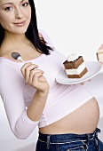 Schwangere Frau, einen Teller mit Kuchenstück haltend
