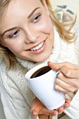 Young woman holding mug of hot drink in her hand