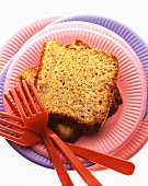 Two pieces of carrot and nut cake on paper plates