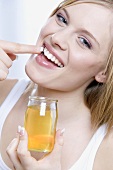 Young woman rubbing honey into her lips