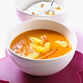 Carrot soup with pieces of orange and cream