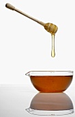 Honey dripping from a honey dipper into a small bowl