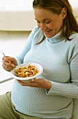 Pregnant woman eating bowl of cornflakes