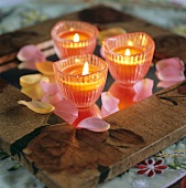 Three candles and rose petals on a table