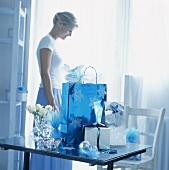 A woman standing behind gifts arranged on a table in blue light