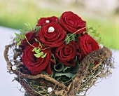 A bouquet of roses with beads surrounded by a wreath of twigs