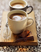 Two mugs of hot chocolate on a wooden board