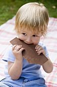 Boy biting into a bar of chocolate