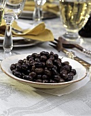 Schwarze Oliven auf Teller am gedeckten Tisch