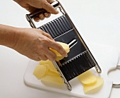 Slicing raw potatoes with cucumber slicer
