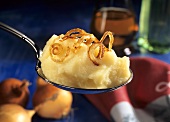 A spoonful of mashed potato with browned onions