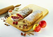An apple strudel and a cherry strudel with icing sugar