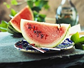 Wassermelonenspalten, eine davon auf Teller mit Besteck